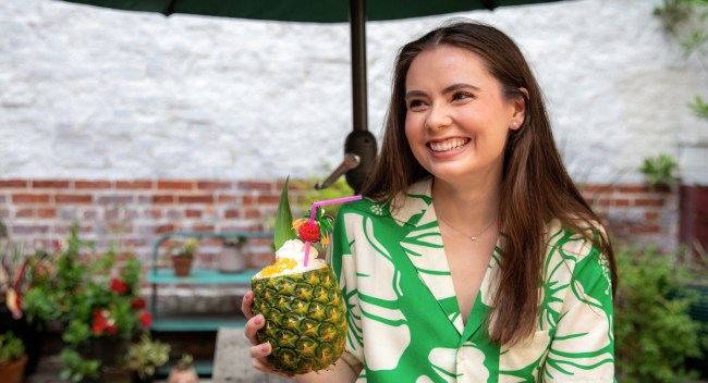Alumna of UL Lafayette's psychology degree program smiles outside, wearing a green Hawaiian-print shirt.